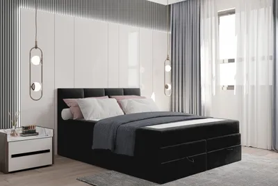 A bedroom scene featuring a black boxspring bed with white and pink pillows and a dark blue duvet.