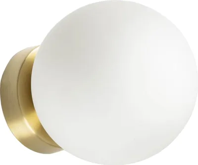 A close-up of a wall lamp with a white glass globe and a gold metal base.