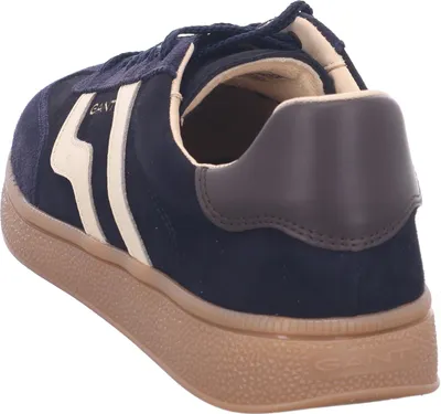 A side view of a navy blue sneaker with cream accents and a brown sole.
