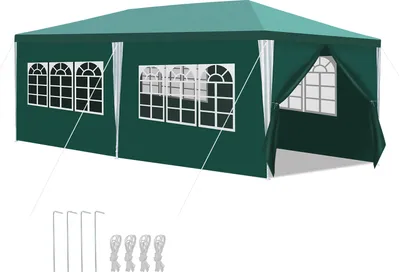 A green tent with white window frames and white curtains, shown from a side angle. Stakes and ties are laid out in front of the tent.