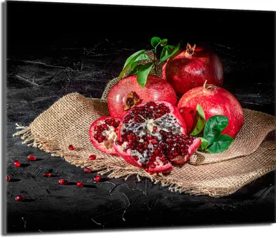 A still life of pomegranates on a burlap cloth against a dark background.