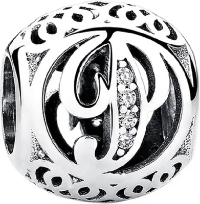 A close-up, studio shot of a silver charm with intricate filigree and small clear stones.