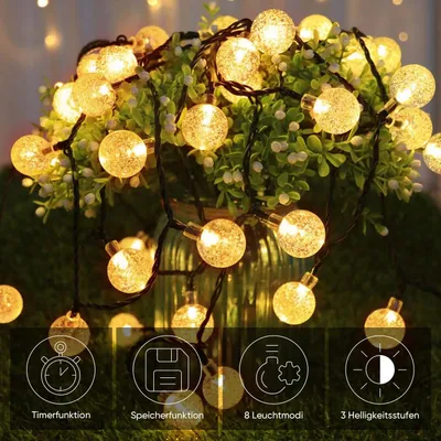 A string of solar-powered LED lights with spherical bulbs, displayed around a potted plant.