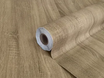 A roll of self-adhesive wood-effect film, designed to mimic the look of oak wood.
