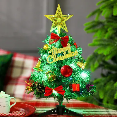 A small, decorated Christmas tree sits on a table with a mug and candy canes nearby.