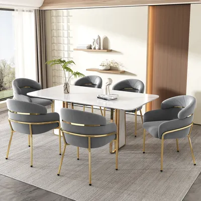 A dining room set with a white marble table and six gray upholstered chairs with gold legs.