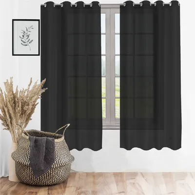 A black sheer curtain hangs in front of a window, with a basket of dried reeds and a decorative basket in the foreground.