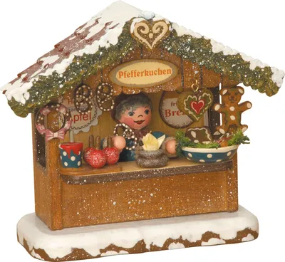 Ein charmantes Markthäuschen mit schneebedecktem Dach präsentiert eine fröhliche Figur umgeben von Pfefferkuchen und weihnachtlichen Dekorationen in einer gemütlichen Szenerie