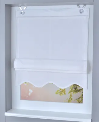 A white Roman blind with a scalloped hem is shown hanging in a window.