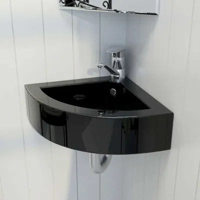 A black corner sink with a silver faucet is mounted on a white paneled wall.