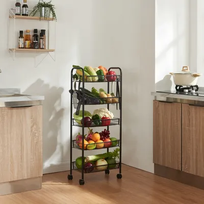 A kitchen scene with a multi-tiered rolling cart filled with fresh produce, next to kitchen cabinets and a stovetop with a pot.