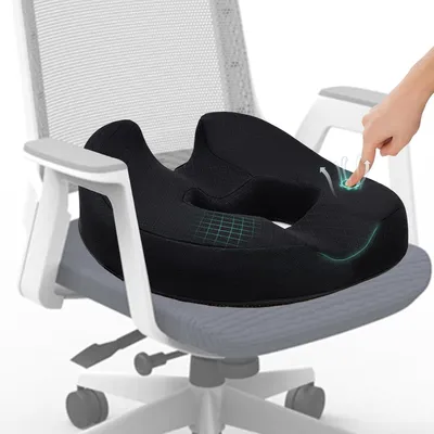 A black memory foam seat cushion is placed on an office chair, with a hand pointing to a highlighted area on the cushion.