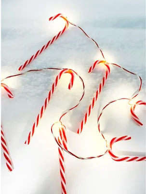 A string of candy cane-shaped LED lights on a white, snowy surface.
