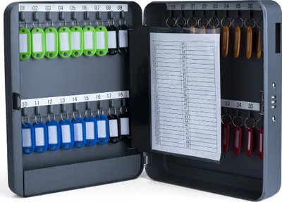 An open key cabinet with keys and labels inside, and a list of numbers on a paper.