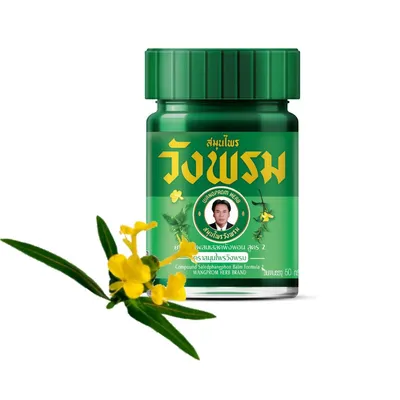 A green bottle of WangProm herbal balm is shown with a sprig of yellow flowers and green leaves in the foreground.
