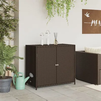 An outdoor patio scene with a brown poly rattan cabinet, plants, and a watering can.