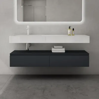 A modern bathroom vanity with a white sink and dark gray cabinet, set against a gray concrete wall.
