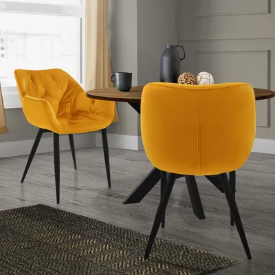 Two yellow velvet dining chairs are placed around a wooden dining table in a dining room setting.