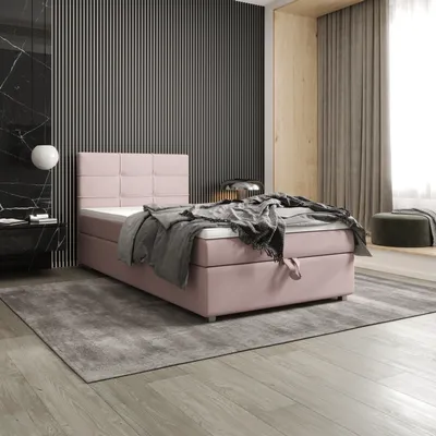 A bedroom scene featuring a pink boxspring bed with a gray blanket and pillows, set against a modern wall and wooden accents.