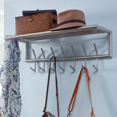 A wall-mounted coat rack with a shelf above it, holding a basket and a hat. Several bags and a scarf are hanging from the hooks below.