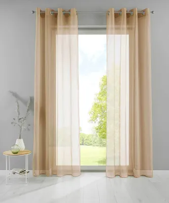Two sheer curtains hang in front of a window, with a small table and vase to the left.