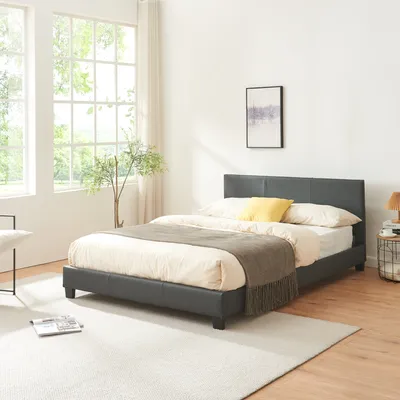 A bedroom scene with a bed, rug, and large windows.
