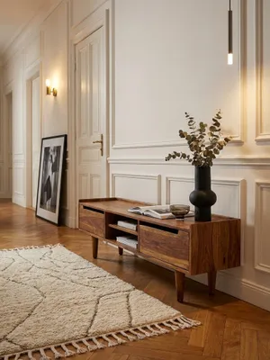 Design TV-Lowboard aus massivem Sheesham-Holz in einem modernen Wohnzimmer, stilvoll unter einem Fernseher platziert und mit minimalistischer Deko._#sku_SAFWL6.553#