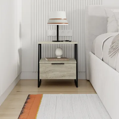 A bedside table next to a bed, with a lamp and a book on it.