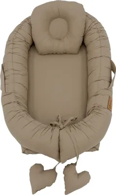 A top-down view of a baby nest with a headrest and two heart-shaped decorative elements.
