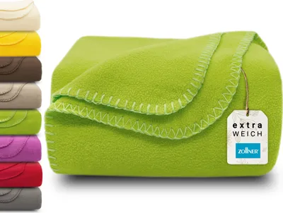 A folded green fleece blanket with a tag attached, and a stack of other colored blankets to the left.