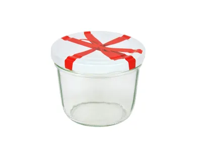 A clear studio shot of a glass jar with a white lid decorated with a red ribbon pattern.