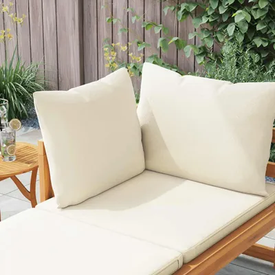 Outdoor lounge chair with cushions on a wooden deck, next to a small table with a drink.