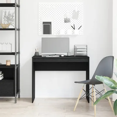 A black desk with a computer and office supplies in a room.