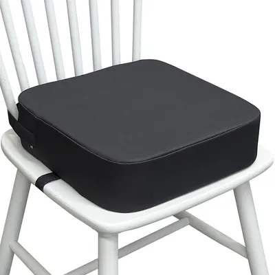A black booster seat is placed on a white chair.