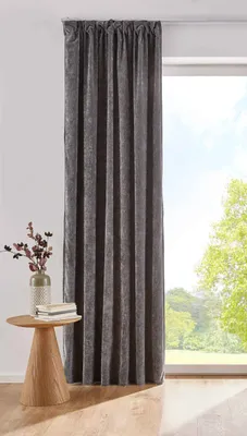 A dark gray curtain hangs next to a window, with a small wooden table and a vase of flowers in the foreground.