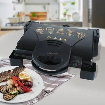 A black electric grill is shown on a table with a plate of grilled food in front of it. The background is a blurred kitchen scene.