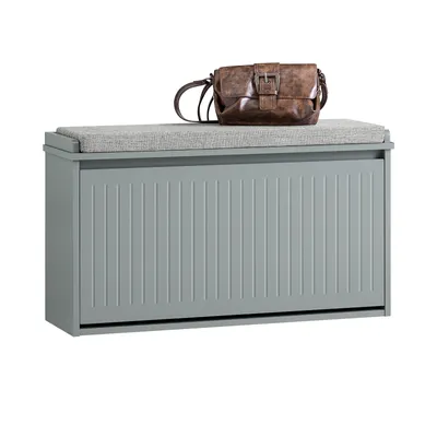 A grey shoe cabinet with a grey seat cushion and a brown handbag on top, isolated on a white background.