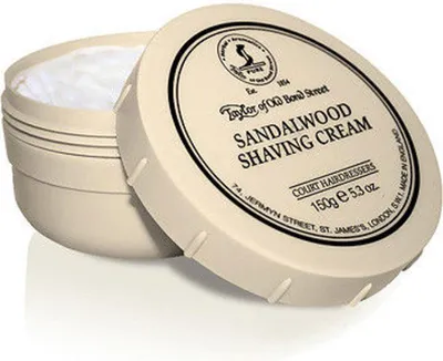 A shaving cream jar with its lid open, showing the cream inside.