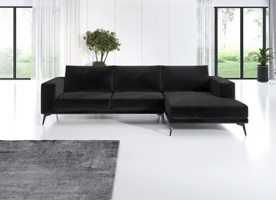 A black sectional sofa is shown in a modern living room setting with large windows and sheer curtains.