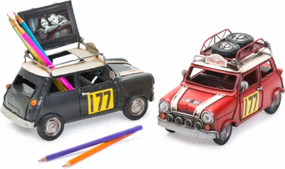 Two decorative metal cars, one red and one black, displayed on a white background. The black car has pencils in it and a photo frame on top. The red car has spare tires on its roof.