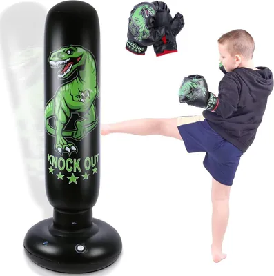 A young boy is kicking an inflatable punching bag with a dinosaur design. Boxing gloves are also visible.