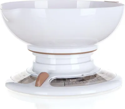 A white mechanical kitchen scale with a bronze accent sits on a reflective white surface.