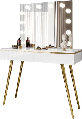 A white vanity table with gold legs and a mirror with lights.