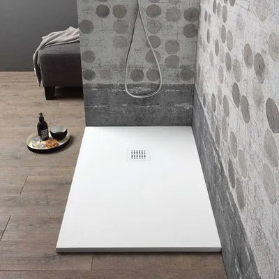 A modern bathroom with a white rectangular shower tray, grey patterned tiles, and wooden flooring.