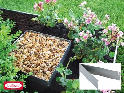 A garden bed with a metal edging, filled with gravel and surrounded by plants and flowers.