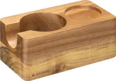 A wooden coffee tamper station with two circular indentations, one larger and open on the side, and a smaller one recessed on the top.