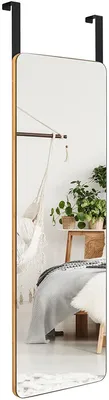 A bedroom scene with a mirror hanging over a door, reflecting a bed and plants.