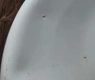A close-up view of a white pot with two small dark spots on its surface.