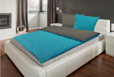 A bed with turquoise and gray bedding in a bedroom.