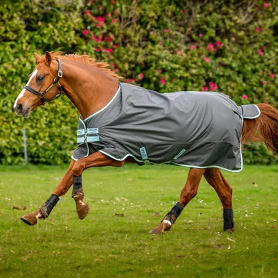 A horse running in a field wearing a blanket.